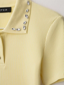 Macro detail of pale yellow knit polo shirt with rhinestone embellishments on the collar