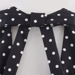 Dettaglio del fiocco a pois neri e bianchi sulla scollatura dell'abito in chiffon