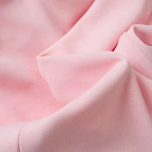 Macro detail of soft light pink textured fabric with fine stitching and soft drape