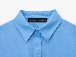 Detailed macro view of light blue linen shirt collar with button and brand label