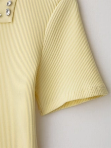 Detail of light yellow knit top featuring vertical ribs and sparkly rhinestone collar trim