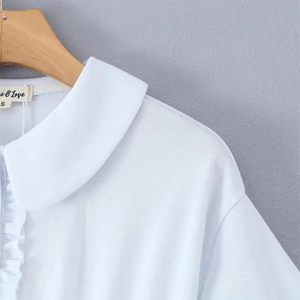 White slim-fit dress with ruffled button placket and Peter Pan collar on wooden hanger