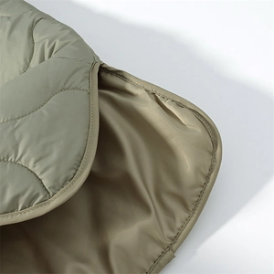 Detail of olive green quilted jacket featuring wavy stitching and smooth satin lining