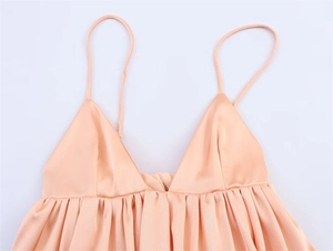 Close-up of peach satin camisole featuring smooth silk texture and delicate pleat details