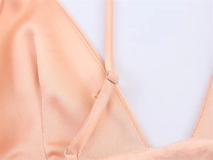 Detailed close-up of pink satin camisole showing thin adjustable silver metallic straps