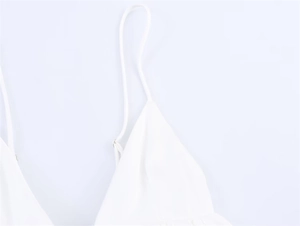 Detailed close-up of white spaghetti strap and V-neckline on a cotton linen camisole top