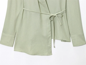 Detail of light green wrap shirt featuring cotton linen texture and waist tie detail