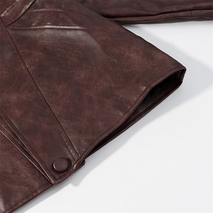 Detail der Kunstlederstruktur und dekorativen Seitengurte an dunkelbrauner Jacke