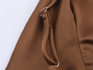 Detailed macro view of the brown satin fabric with adjustable metal spaghetti strap buckle