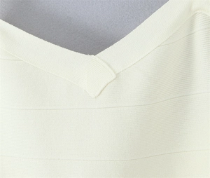 Détail de la maille côtelée blanche et couture plate du décolleté croisé de la robe