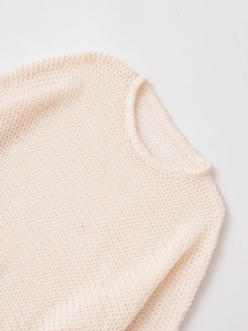 Detailed close-up of beige knit sweater featuring hollow-out texture and round neckline