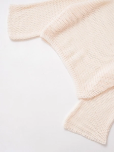Macro shot of cream knit fabric texture with soft wool pattern and fine stitch detail