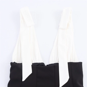 Detail of elegant black and white V-neck dress featuring stylish bow tie straps