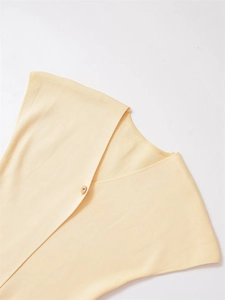 Detail of a creamy yellow knit sweater showing a V-neck and a gold button on fine fabric