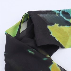 Detail of sheer chiffon dress fabric featuring bold green and yellow abstract dye print