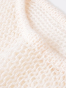 Close-up detail of soft cream chunky knit fabric with premium wool texture and pattern