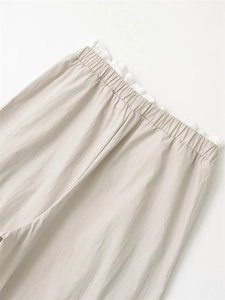 Detailed close-up of wide-leg trousers featuring elastic waistband and frill trim detail