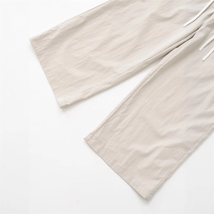 Detail of light beige wide-leg pants with elastic drawstring waist and textured fabric