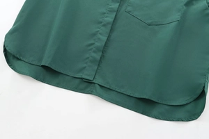 Detailed view of curved hem and front pocket on deep green poplin cotton shirt