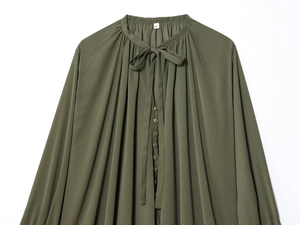 Detail of olive green pleated shirt featuring bow-tie collar and textured fabric