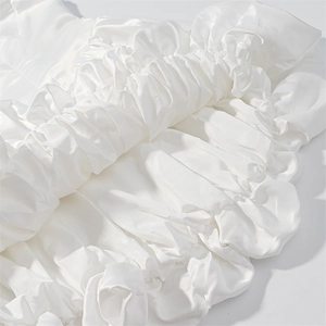 Detailed view of layered white satin ruffles and elegant pleated fabric texture