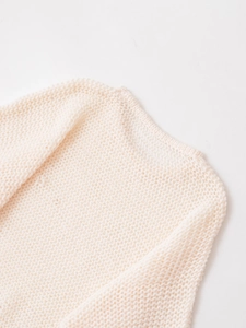 Detailed macro view of the knitted hollow texture and neckline on this cream knit sweater