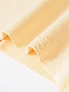 Macro detail of high-density pale yellow knit fabric with fine texture and soft drape