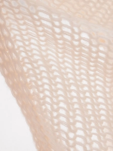 Close-up detail of soft beige hollow knit fabric showing delicate mesh texture and weave