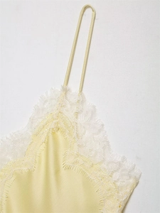 Detailed close-up of delicate white eyelash lace on a pale yellow satin camisole top