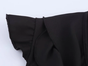 Vue macro détaillée des manches à volants superposés et texture en mousseline d'une chemise noire