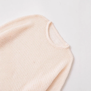 Detail view of the open-knit texture and crew neckline on this beige loose knit sweater