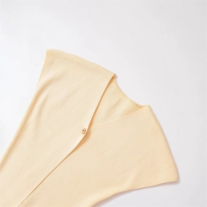 Detail view of the V-neckline and shiny gold button on this minimalist knit top