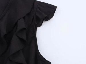 Détail de volants multicouches sur chemisier noir en tissu tissé léger pour femme