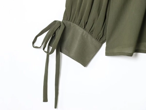 Detail of army green pleated cuffs with elegant bow-knot tie on a long-sleeve blouse