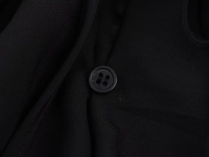 Détail d'un bouton classique à quatre trous sur un tissu noir à armure toile