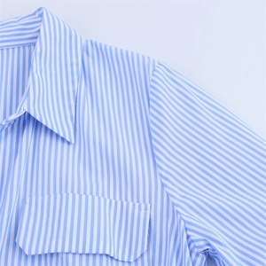 Détail de la robe chemise en popeline à rayures bleues et blanches avec revers et poche