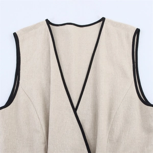 Close-up of beige linen sleeveless dress with black contrast trim and deep V-neckline
