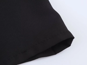 Gros plan sur la texture du tissu crêpe noir et les coutures soignées de l'ourlet
