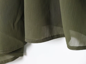 Detail of olive green pleated chiffon fabric with fine vertical texture and hemline