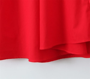 Gros plan détaillé de l'ourlet à double surpiqûre sur le tissu de la robe rouge