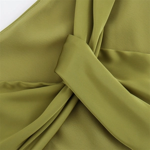 Macro view of olive green satin fabric showing elegant knot and pleated detail design