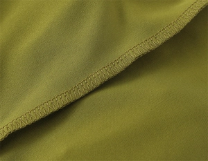 Detailed macro view showing the precise overlock stitching on olive green summer dress fabric