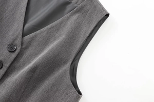 Détail du gilet gris foncé avec col en V, texture en sergé et un bouton noir