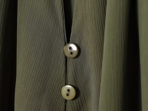 Close-up of olive green blouse fabric texture with two matching resin buttons