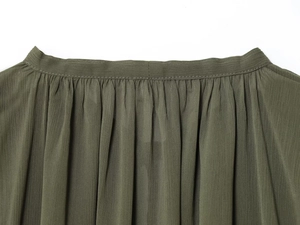 Macro detail of olive green blouse fabric showing elegant pleats and stitching texture