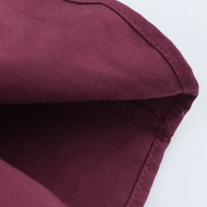 Gros plan des coutures de haute qualité sur le tissu en coton rouge foncé de la robe