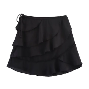 Détail d'une mini-jupe noire à volants multicouches avec lien noué à la taille