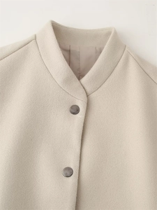 Detail of stand-up collar and circular metal button on beige wool blend jacket