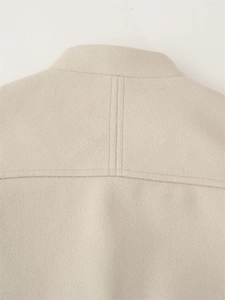 Close-up of beige wool jacket shoulder seams with reinforced double-row stitching