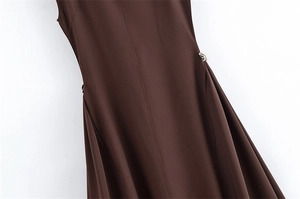 Detail of dark brown sleeveless dress showing vertical stitching and silver metal buckle